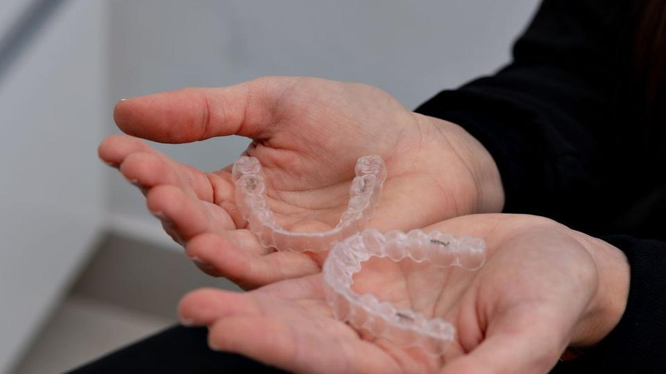 Clear aligner trays held in open hands