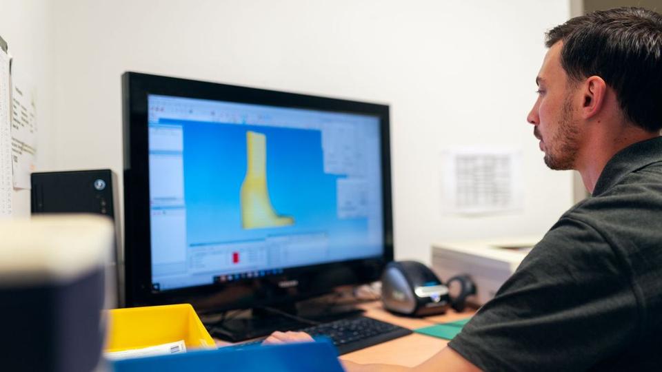 Designer reviewing a 3D part model on a desktop monitor