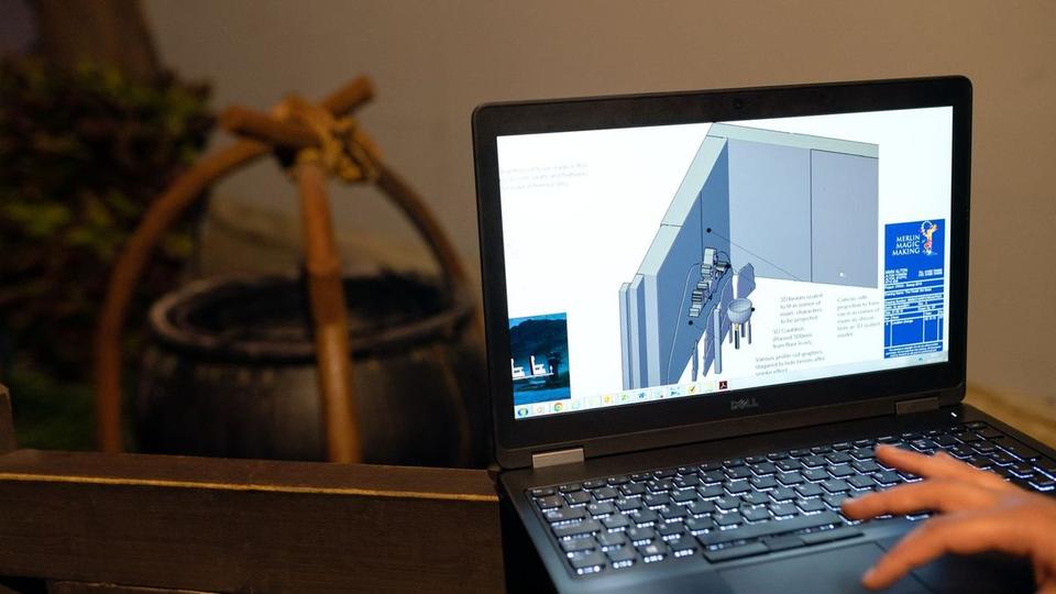 Laptop showing a 3D building model on a wooden desk