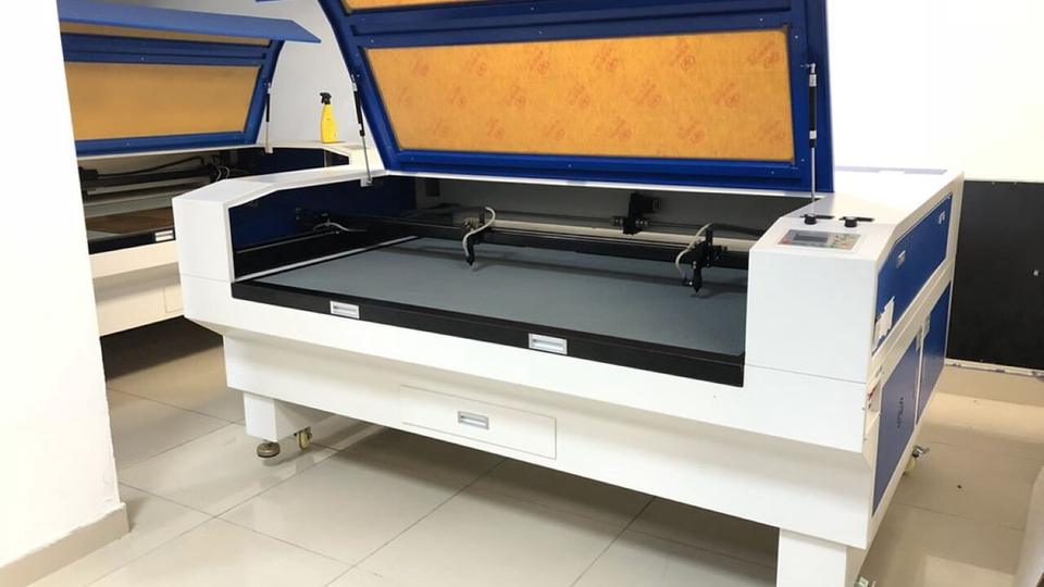 Large CO2 laser cutter with its lid open in a workshop